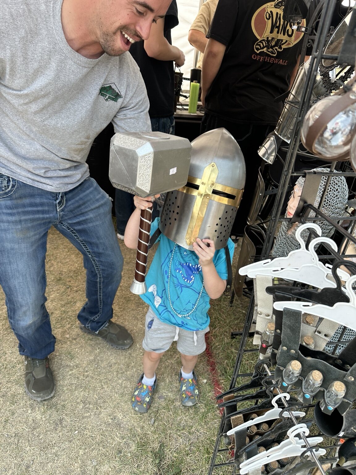 Johnny smiling while Elliot tries on a knight helmet